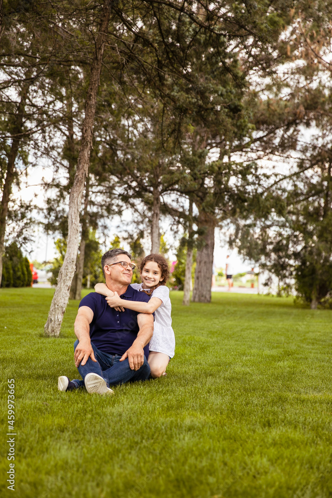 Full length image of a niece hugs her grandfather in the park on a sunny day. Outdoor portrait. Family concept. Full length image of a niece hugs her grandfather in the park on a sunny day. Outdoor portrait. Family concept.