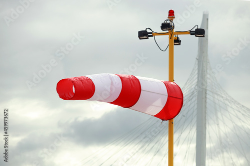 A striped weather vane on a sky background.