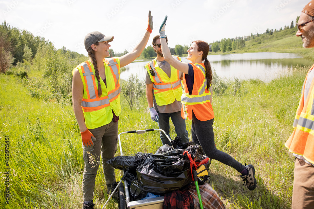 Litter pickers putting full refuse sacks in trolley Stock Photo Adobe