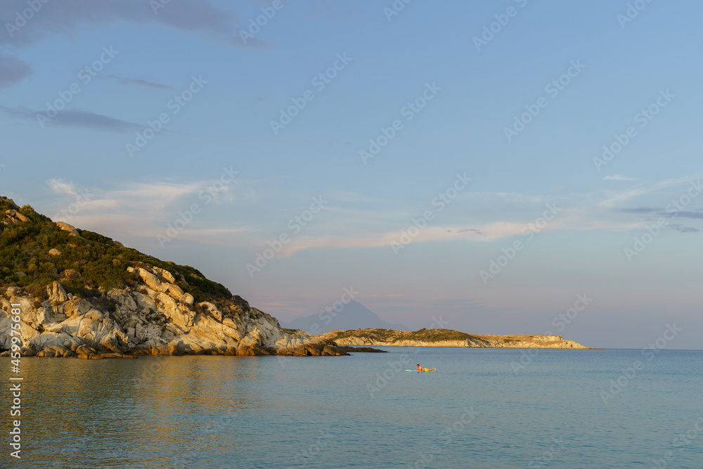 Sea mountain view with man surfing on sup board on sunny day. High quality photo