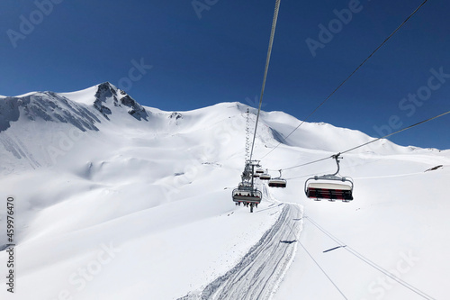 Chairlift lifting people on top of high mountains. Winter sports ski and snowboarding in high mountains.