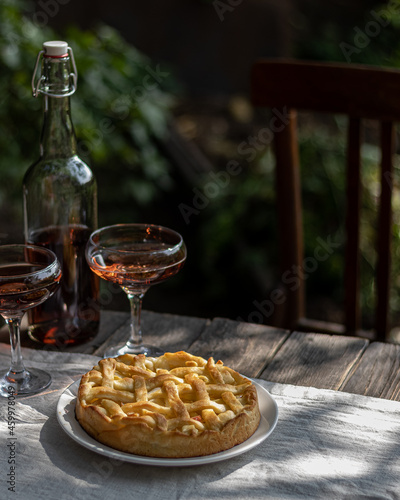 apple pie and wine with glasses on a wooden table in the garden