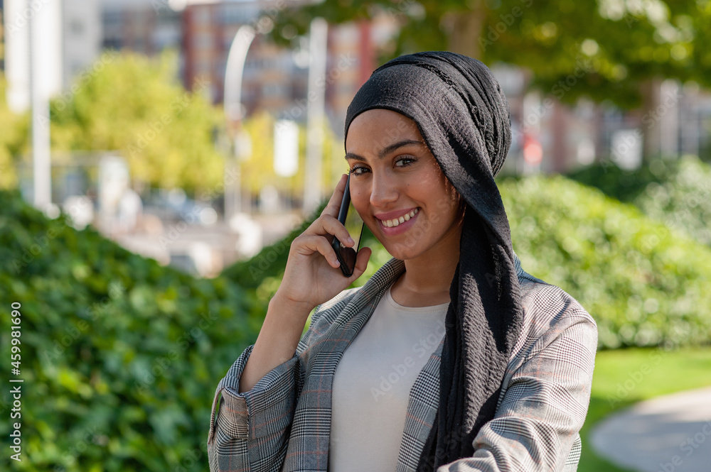 Adult woman smiling talking with her phone in the park looking at camera Adult woman smiling talking with her phone in the park looking at camera