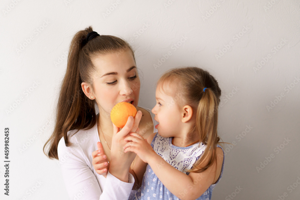happy cheerful funny kids children with mom eat bite fresh fruits and vegetables at home. family eats lunch oranges, citrus apples bananas. Healthy eating, vitamins, diet, vegetarianism menu concepts happy cheerful funny kids children with mom eat bite fresh fruits and vegetables at home. family eats lunch oranges, citrus apples bananas. Healthy eating, vitamins, diet, vegetarianism menu concepts