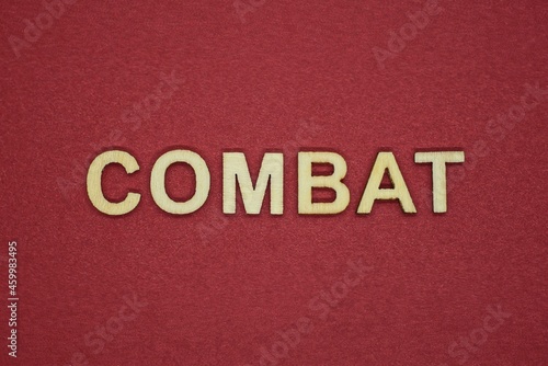 text the word combat from gray wooden small letters on an red table