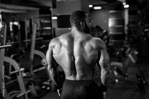Fit young man doing workout at a gym. Sport, fitness, weightlifting, bodybuilding, training, athlete, workout exercises concept. View from the back