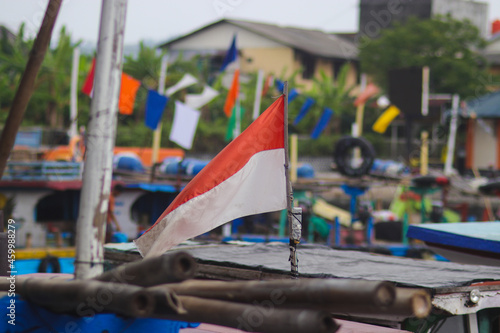 Indonesia red white flag fluttering on a fishing boat with defocused background at Pelabuhanratu Sukabumi Seaport, West Java, Indonesia.