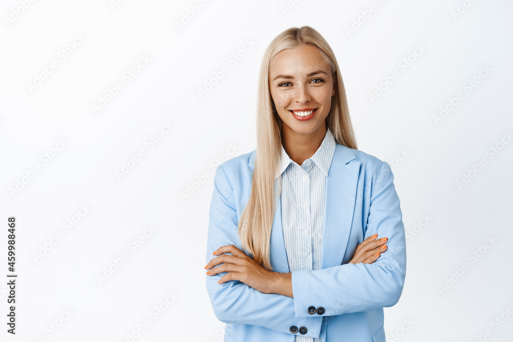 Ambitous young corporate woman in suit, cross arms on chest, smiling and looking confident, standing over white background Ambitous young corporate woman in suit, cross arms on chest, smiling and looking confident, standing over white background