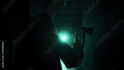 Maniac running for woman with axe in dark corridor. Mystical scary murderer going to kill girl victim, carrying murderous weapon. Halloween costume of killer. Horror scene or nightmare concept. 
