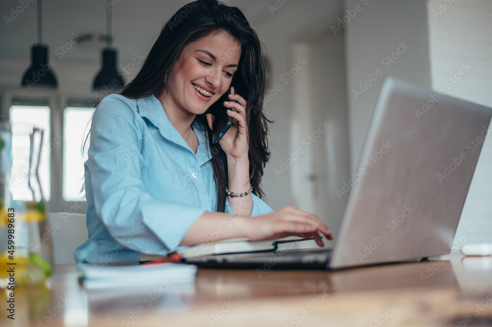 Young beautiful businesswoman using a laptop and a smartphone while in the office Young beautiful businesswoman using a laptop and a smartphone while in the office