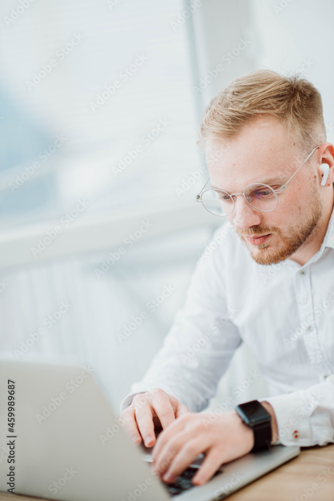 Man in wireless bluetooth headphones works at laptop, video conference Man in wireless bluetooth headphones works at laptop, video conference