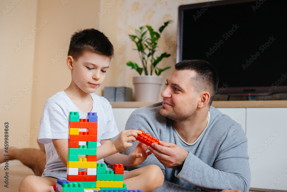 A little boy together with his father is played by a constructor and builds a house. Construction of a family home. A little boy together with his father is played by a constructor and builds a house. Construction of a family home.