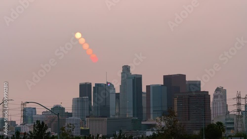 Time lapse day to night transition of red sun over Los Angeles skyline obscured by smoke from KNP Complex wildfire in California in 2021 photo