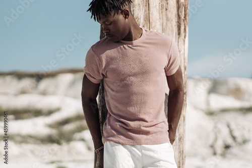 Open full length portrait of stylish handsome man, in stylish clothes, black man posing on sand