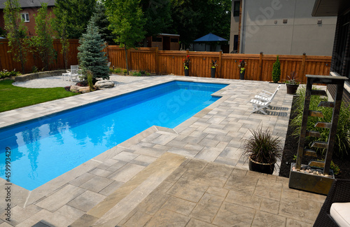 Completed landscaping around new swimming lap pool in back yard with paver patios gardens and lawn Barrie Ontario Canada © Reimar