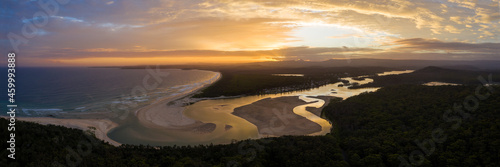 Aereal panoramic view of Cunjurong Point inlet, Lake Conjola, beach and caravan park during sunset with light reflected on water on inlet photo