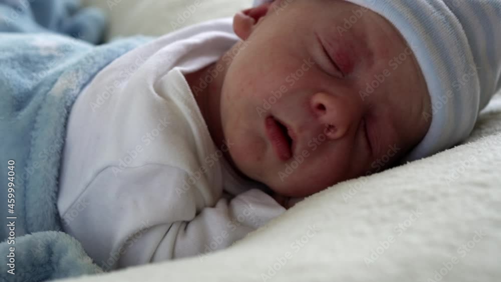 Close-up Crying Newborn Baby Face Portrait Early Days Sleeping On Tummy Blue White Background. Child At Start Minutes Of Life on Hat. Infants, Childbirth, First Moments Of Borning, Beginning Concept Close-up Crying Newborn Baby Face Portrait Early Days Sleeping On Tummy Blue White Background. Child At Start Minutes Of Life on Hat. Infants, Childbirth, First Moments Of Borning, Beginning Concept