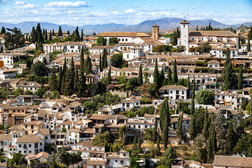 Beautiful panorama of the Albaicín, the historic city center of Granada with its characteristic white house under a picturesque cloudy blue sky, seen from the Alhambra palace, Andalusia, Spain