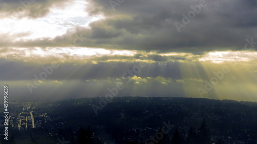 Dramatic sunlight shining through dark clouds over Fraser Valley and Port Moody  BC.