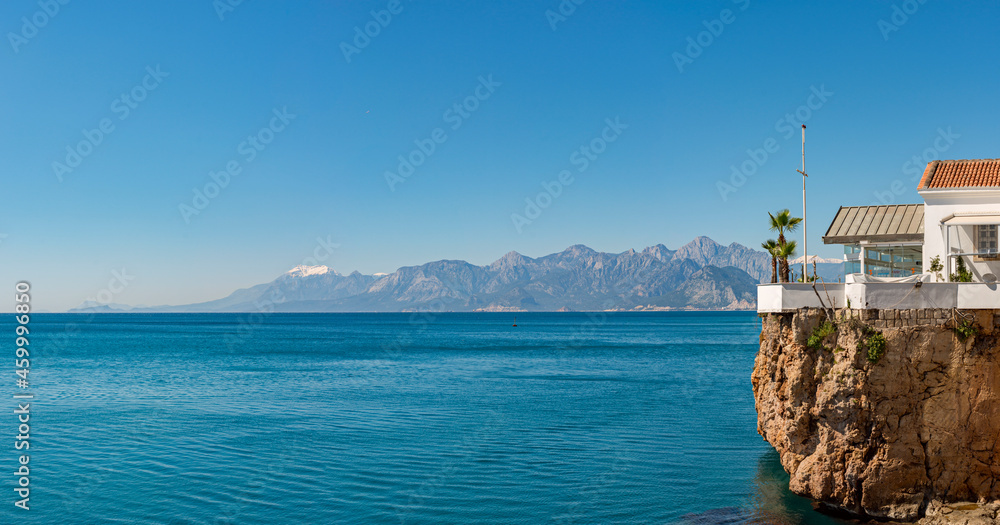 Panoramic of the Turkish coast of Antalya with beautiful beaches and high snow-capped mountains. Glazed gazebo with garden and palm trees