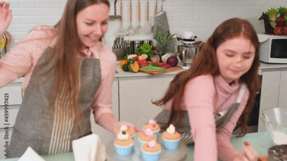 Caucasian mother and daughter enjoy to cook and prepare cupcake in their kitchen. Concept of happy family with new normal lifestyle. Caucasian mother and daughter enjoy to cook and prepare cupcake in their kitchen. Concept of happy family with new normal lifestyle.