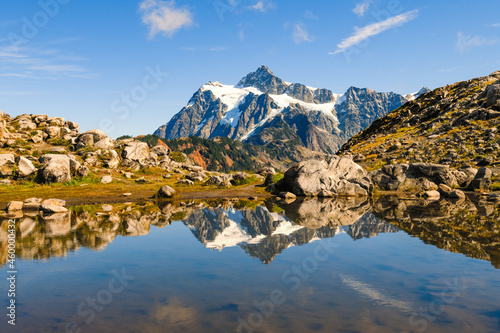 Mount Shuksan reflects in a pool of water on Artist Ridge Trail in Northwest Washington State on a blue sky day in fall