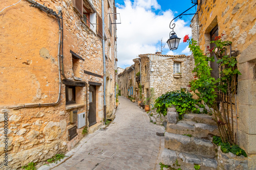 Fototapeta Naklejka Na Ścianę i Meble -  A narrow alley of apartments and homes in the historic center of the walled medieval village of Tourrettes-Sur-Loup in the Alpes-Maritimes section of southern France.
