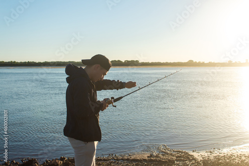 Man preparing his fishing rod at the edge of the river.