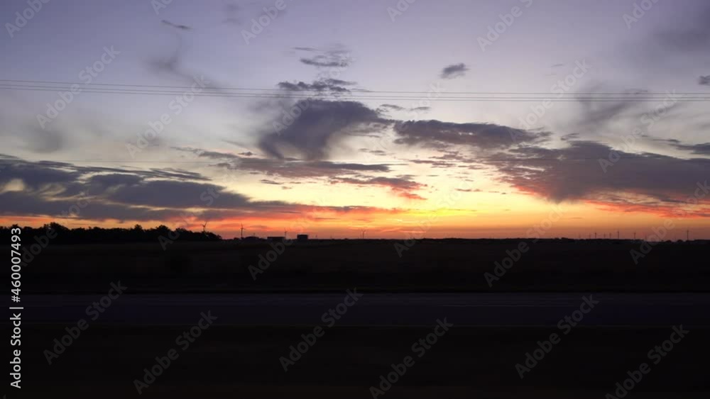 Driving POV at dawn with wires dipping between electric poles