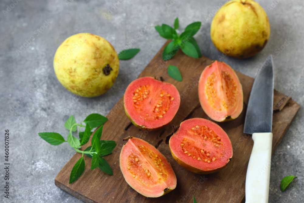 Guava fruit or Psidium Guava on wooden chopping board , on grey grainy background. Guava fruit or Psidium Guava on wooden chopping board , on grey grainy background.