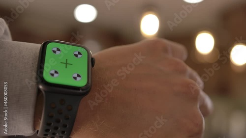 A man uses a smart watch with a chromakey on a green screen. A smart watch on a man's wrist. A layout for tracking or viewing content in 4K format. Close-up. High quality 4k footage