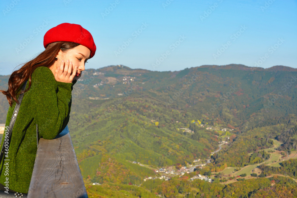 秋の紅葉の風景を眺める女性