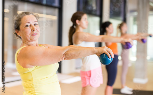 Sporty women doing exercises with pilates balls during group training at gym