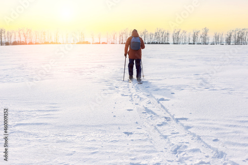 A man with backpack on skis in snowy field. Freedom, adventure concept. Loneliness.