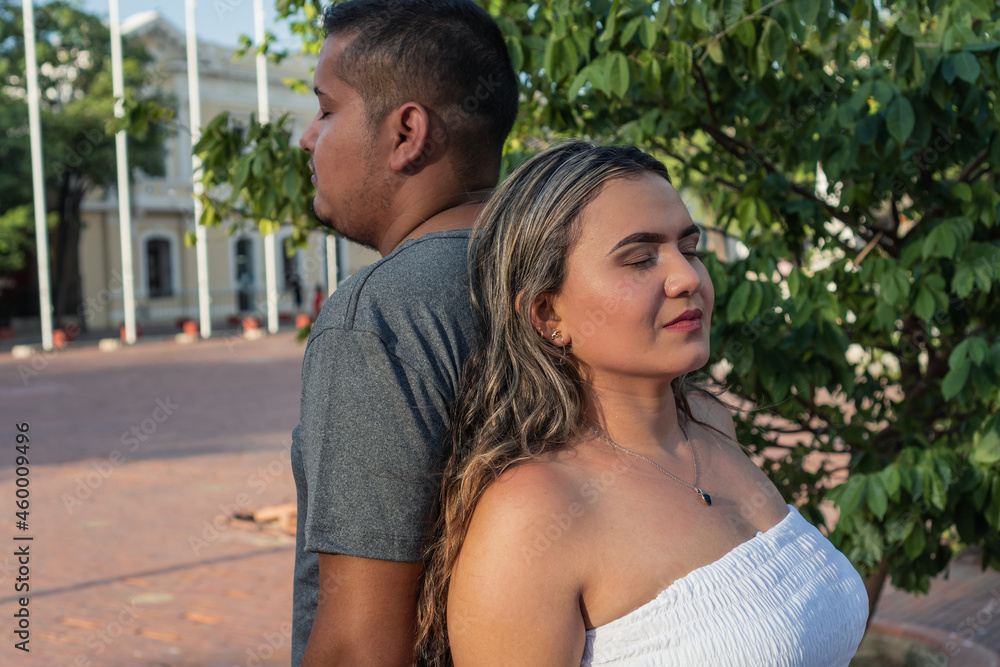 Hispanic couple with their backs to each other with their eyes closed Hispanic couple with their backs to each other with their eyes closed