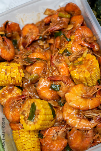 "Udang Goreng Saos Tiram" or fried prawns or shrimp in oyster sauce. Serving with boiled corn