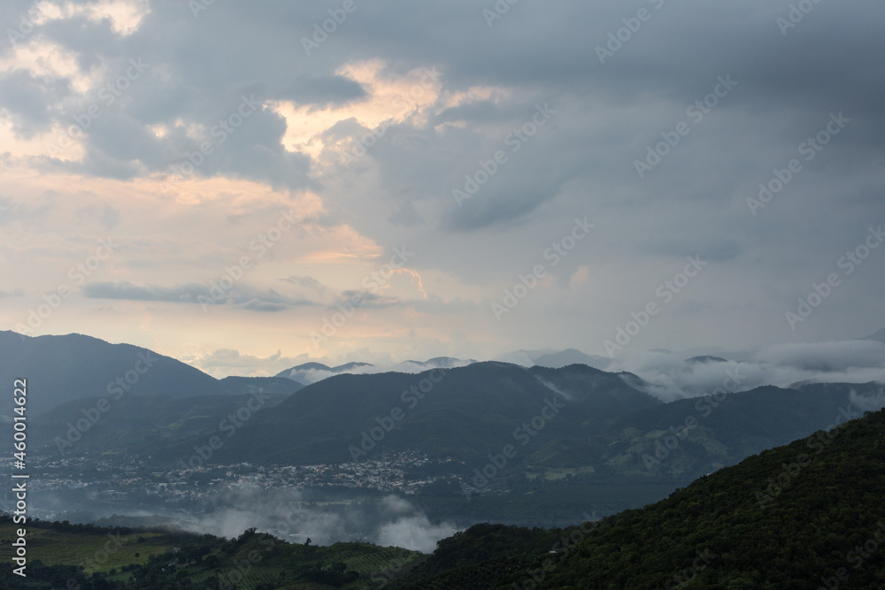 Dramatic image of Caribbean mountains after a rain storm in a small town in Dominican Republic, with cloudy skies and fog.