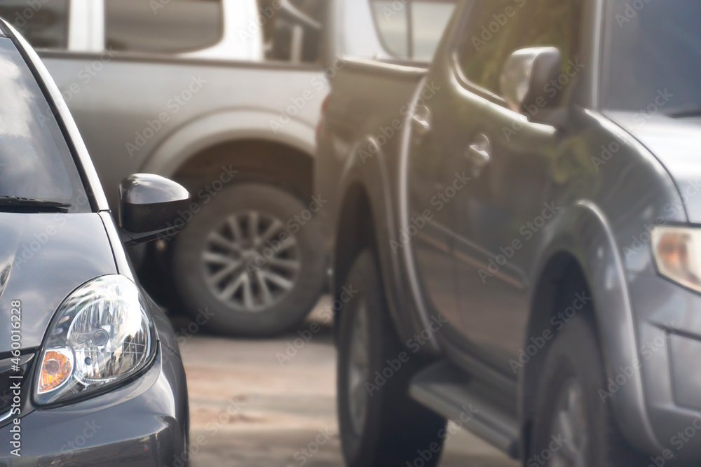 Front view of a gray car parked in a parking lot. With blurred of  other cars parked sideways and behind.