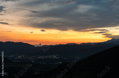 Dramatic sunset image of the Caribbean mountains with a small town with street lights in the Dominican Republic. © Todd