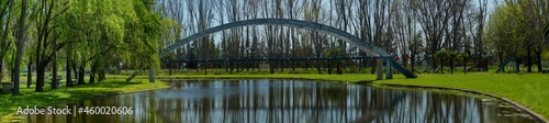 Panoramic view of an old concrete pedestrian bridge over a small lake in a park located in General Alvear, Buenos Aires © Christian