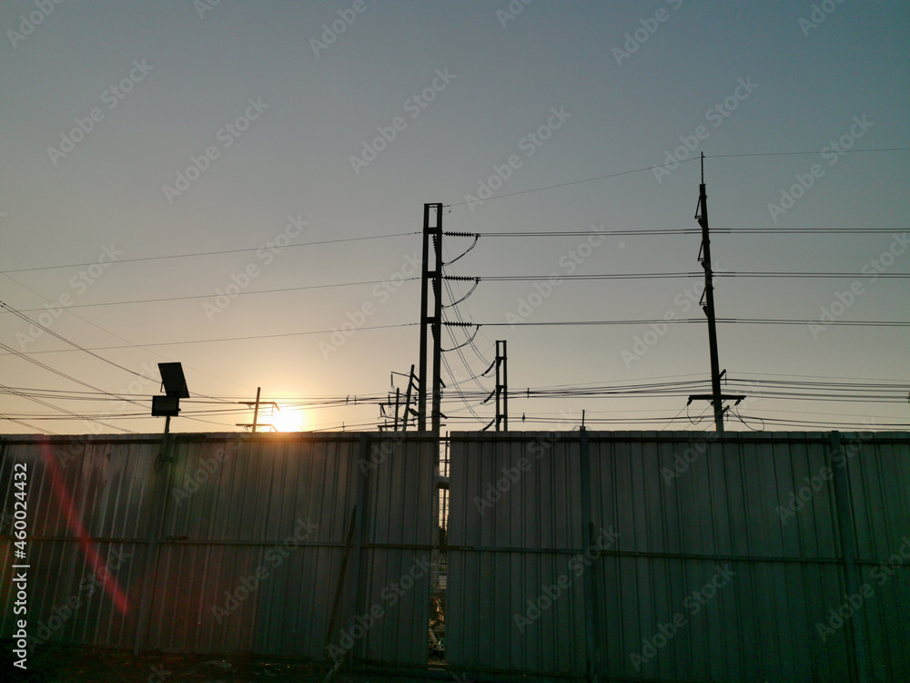 Corrugated Metal Fence with Utility pole in sunset time, electric wire floating in overhead Corrugated Metal Fence with Utility pole in sunset time, electric wire floating in overhead