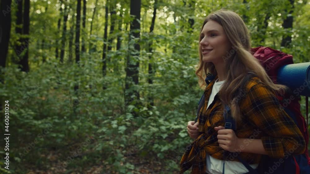 Young happy active lady backpacker walking in autumn wood, enjoying nature, carrying backpack with equipment on back Young happy active lady backpacker walking in autumn wood, enjoying nature, carrying backpack with equipment on back