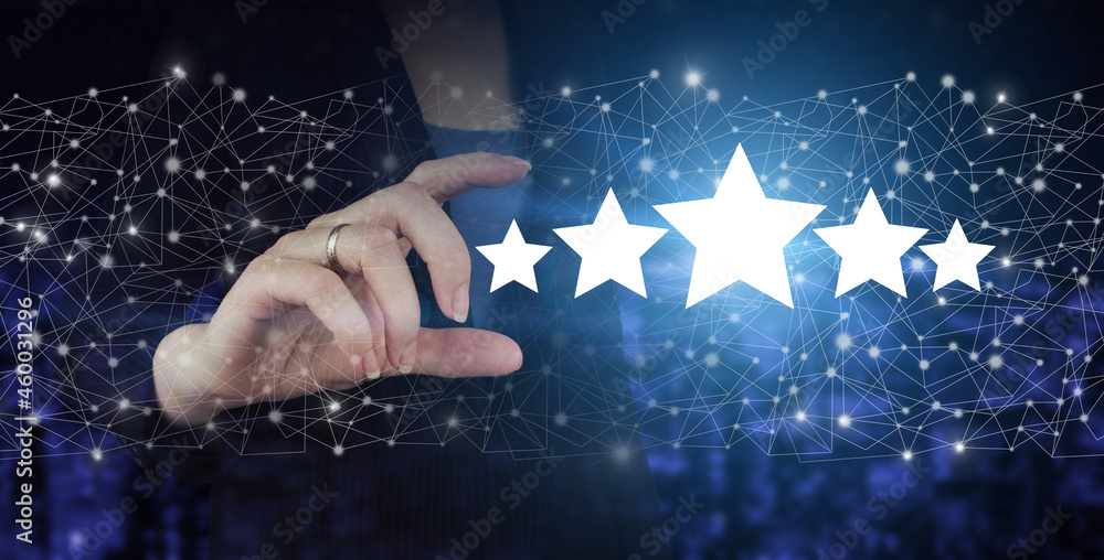 Fototapeta premium Review, Rating,Satisfaction. Hand hold digital hologram five stars sign on city dark blurred background. Product service evaluation concept.