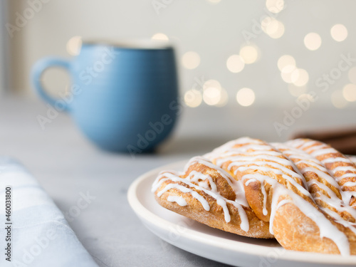Cinnamon roll or cinnamon bun Dessert on plate with blue cup of coffee. Classic American or French bakeries. Bokeh photo