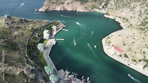 Aerial panoramic view of Balaklava landscape with boats and sea in marina bay. Crimea Sevastopol tourist attraction. Drone top view shot of port for luxury yachts, boats and sailboats.