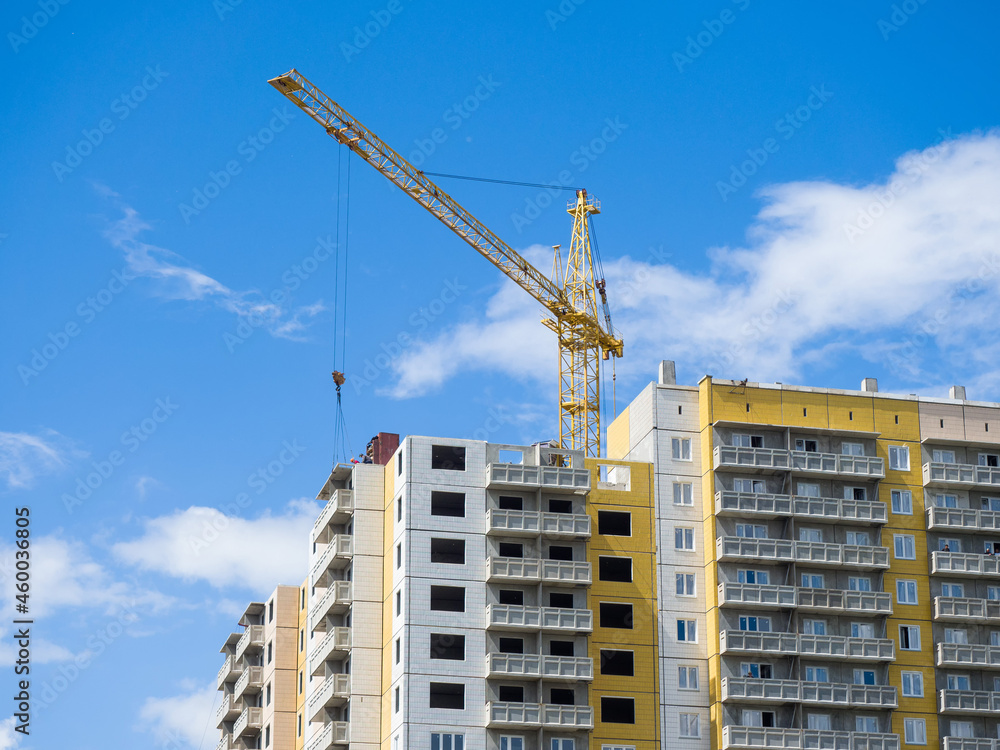 Crane is building a new residential high-rise building. Construction site against the sky. Sunny summer day Crane is building a new residential high-rise building. Construction site against the sky. Sunny summer day