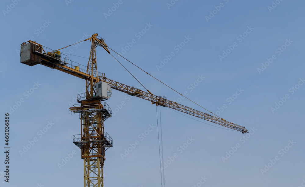 High-rise construction crane. Background - blue sky. Urban construction concept. High-rise construction crane. Background - blue sky. Urban construction concept.