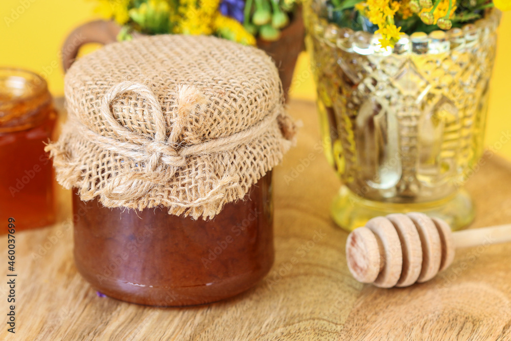 Jar with honey on wooden board.