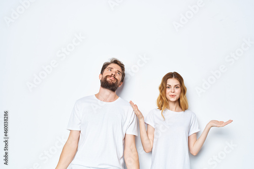 cheerful young couple in white t-shirts and jeans studio posing light background