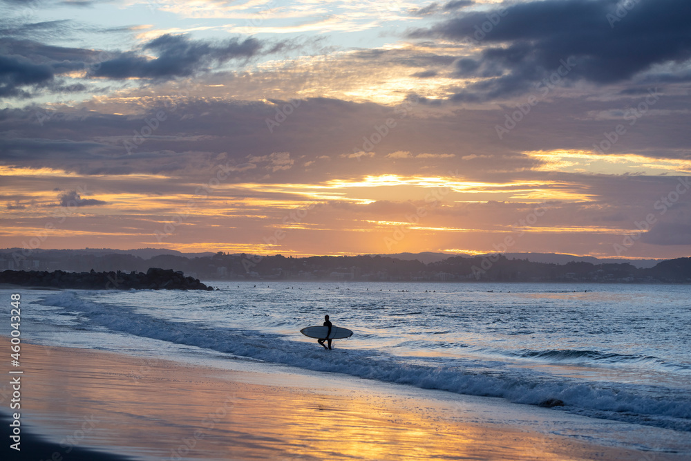 Unidentified surfers silohuettes on Coolangatta Beach in Queensland with a dramatic sunset